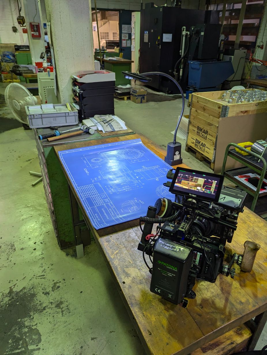 Professionelle Filmkamera neben einer technischen Zeichnung in der Fertigung von Behrens Feinwerktechnik