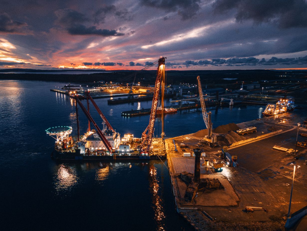 Arbeitsschiff und Schwerlastkräne im Hafen Mukran bei Abendlicht